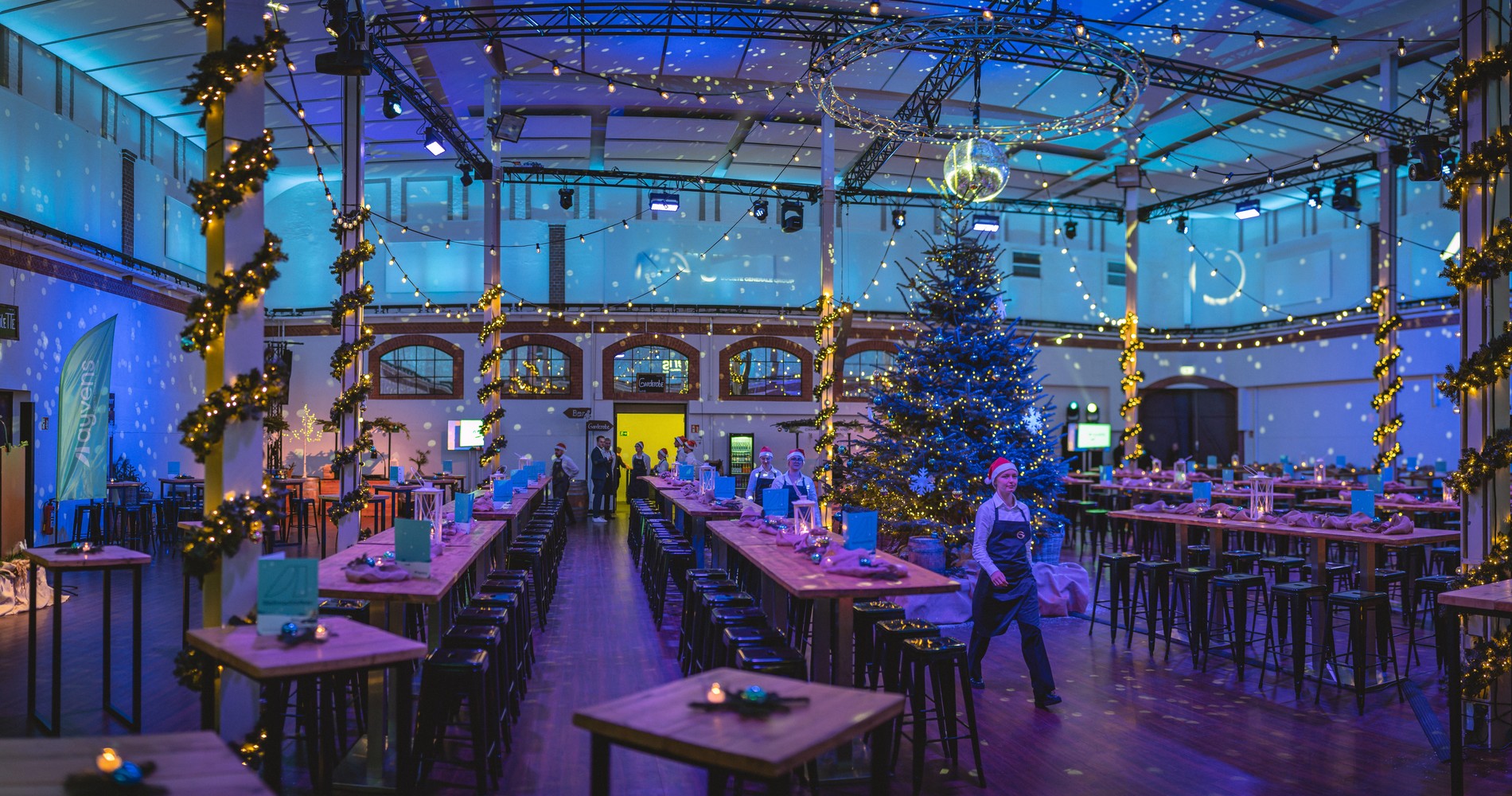 Weihnachtlicher Flair und Dekoration mit Stehtischen, Serviekräften und einem Tannenbaum in der Dressurhalle by Gerresheim im Tierpark Hagenbeck